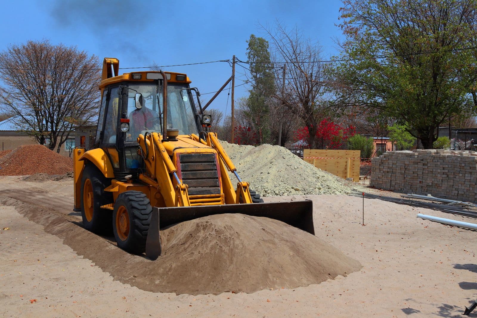 Yellow backhoe loader moving earth on a construction site